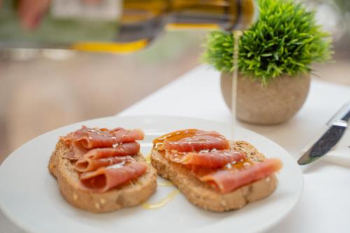 Un plato blanco con dos rebanadas de pan con tomates encima. en Hotel RH Sorolla Centro, en Valencia