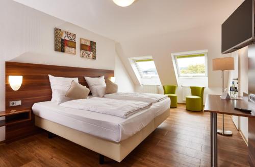 a bedroom with a bed and a desk and chairs at ante porta DAS STADTHOTEL in Trier