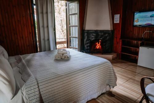 um quarto com uma cama com 2 toalhas e uma lareira em Pousada Bramasole em Monte Verde
