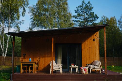 Cabaña de madera pequeña con mesa y sillas en MISI domek, en Kadłubówka