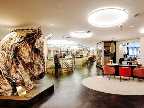 a man standing in a restaurant with a large fish sculpture at Grand Hotel Bregenz - MGallery Collection in Bregenz
