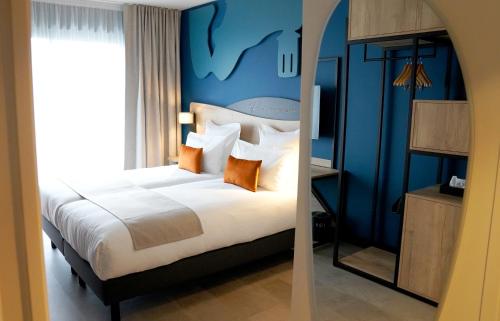 a bedroom with a large bed with a blue wall at Hotel OstOria, BW Signature Collection in Marsac-sur-lʼIsle