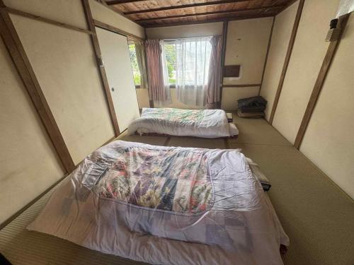 two beds in a small room with a window at くりのやかた in Kunisaki