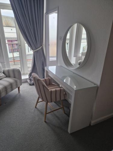 a white dressing table with a mirror and a chair at Southcliffe hotel in Bridlington