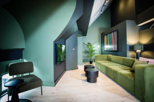 a living room with a green couch and a chair at Urban Jungle by Domu Stays in Manchester