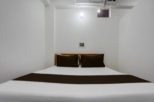 Cama en habitación blanca con 2 almohadas negras en HOTEL O BABA PREM HOTEL, en Bihta