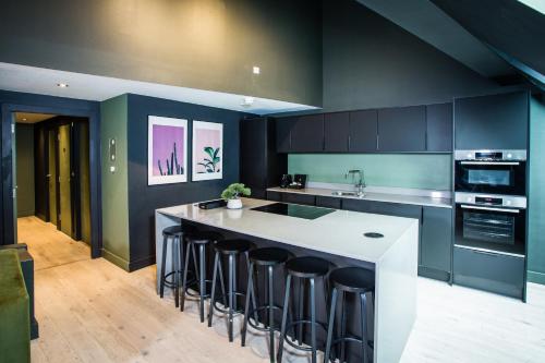 a kitchen with a large island with bar stools at Urban Jungle by Domu Stays in Manchester