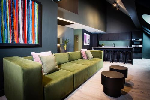 a living room with a green couch and a kitchen at Urban Jungle by Domu Stays in Manchester