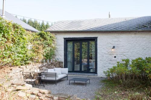 een patio met een bank en een tafel voor een gebouw bij La Chambre de la Gotale in Manhay