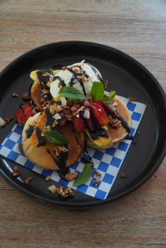 un plato negro con un plato de comida en una mesa en QINARA, Guesthouse Close to Diamond Beach, Nusa Penida, en Polilit