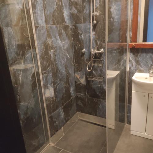 a shower with a glass door in a bathroom at Mieszkanie do wynajęcia in Ostróda