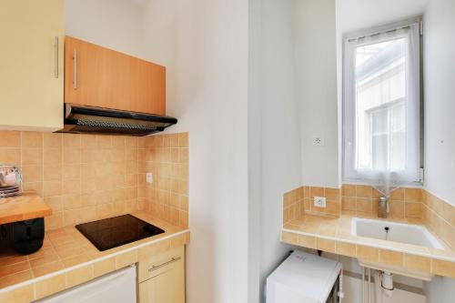 una piccola cucina con lavello e finestra di INVALIDES - TOUR EIFFEL a Parigi