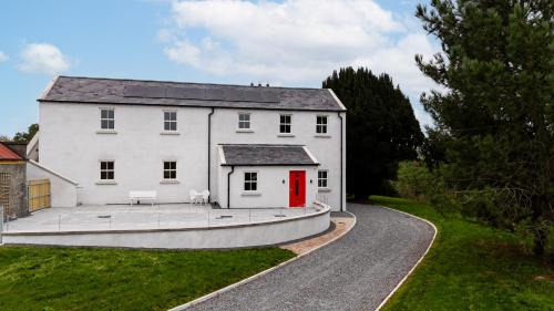 a white house with a red door and a driveway at Whitehill House Farm Banbridge in Banbridge