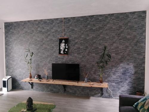 a living room with a tv on a brick wall at Getaway to Mauritius - Évasion à Île Maurice in Eau Bleue