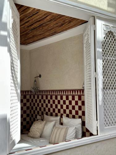 a window in a room with a checkered wall at Riad El Badun in Marrakesh