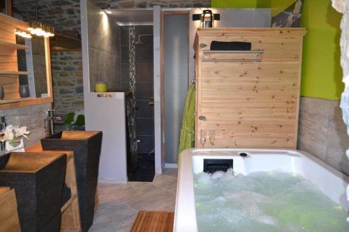 a bathroom with a bath tub with a wooden wall at Loft Cocoon in Mostuéjouls