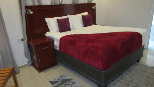 a bedroom with a large bed with a red blanket at Lilly Petals Guest House in Maun