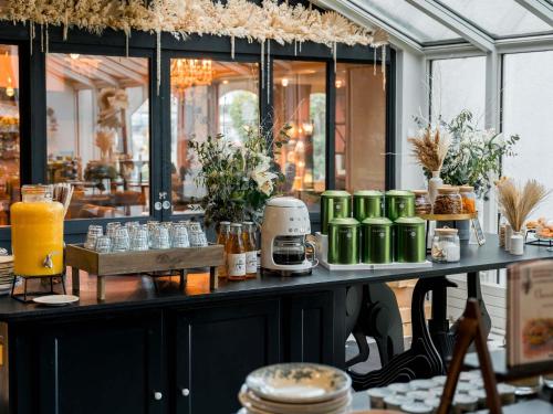 un mostrador en un restaurante con una mesa con bebidas en Hotel Mercure Parc du Coudray - Barbizon, en Le Coudray-Montceaux