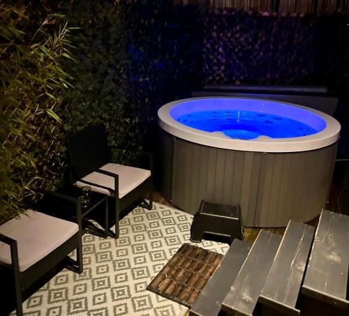 bañera de hidromasaje con 2 sillas y mesa en Cozy tiny house with jacuzzi , garden and free parking near Amsterdam, en Vijfhuizen
