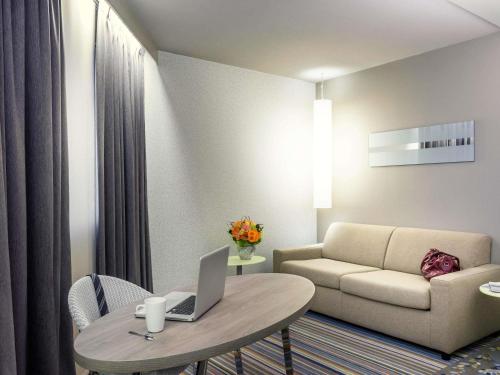 a living room with a couch and a table with a laptop at Mercure Paris Val de Fontenay in Fontenay-sous-Bois