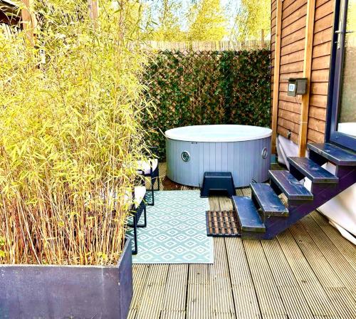 un jacuzzi installé sur une terrasse avec des bancs dans l'établissement Tiny house with garden and jacuzzi near Amsterdam, à Vijfhuizen