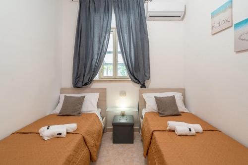 two beds in a small room with a window at Villa Gardenia fronte mare in Santa Maria Del Focallo