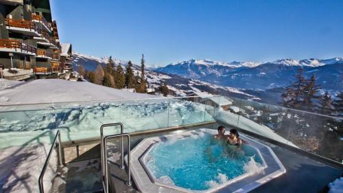 2 personnes dans un bain à remous au sommet d'une montagne dans l'établissement Les Cerfs - Appartement & Studio - ANZERE, à Anzère