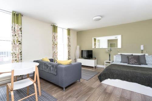 a bedroom with a bed and a couch and a table at Walled City Apartments in Derry Londonderry