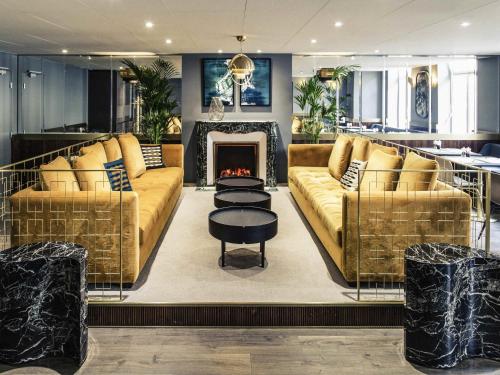 a living room with two couches and a fireplace at Mercure Nancy Centre Place Stanislas in Nancy
