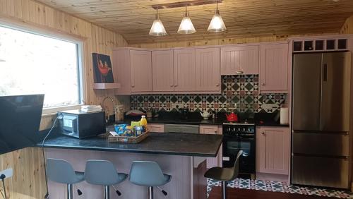 une cuisine avec des armoires roses et un comptoir noir dans l'établissement Stream-side cabin and sauna, à Ballyduff