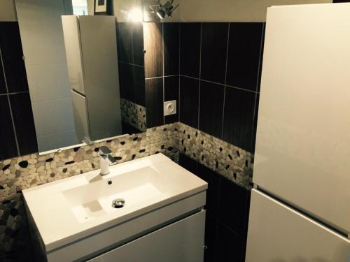 een badkamer met een witte wastafel en een spiegel bij Maison proche mer Langueux in Langueux