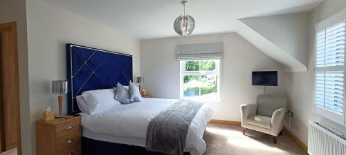 a bedroom with a bed with a blue headboard and a chair at Gateside Lodge in Portrush