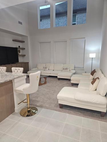 a living room with white couches and a tv at Talia Heaven in Mesquite