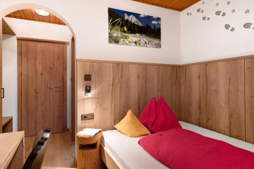 a bedroom with a bed with red and yellow pillows at Veltierhof Villnöß in Funes