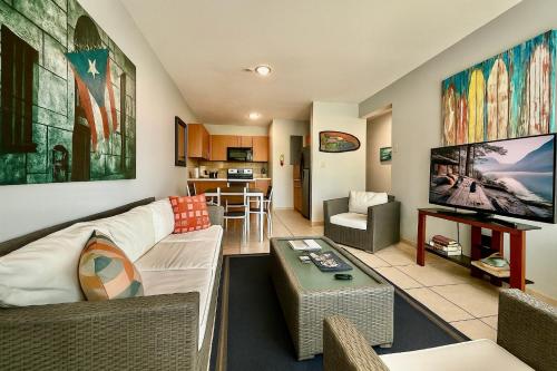 a living room with a couch and a tv at Ocean Terrace 202 a 4 min walk to Sandy Beach in Aguada