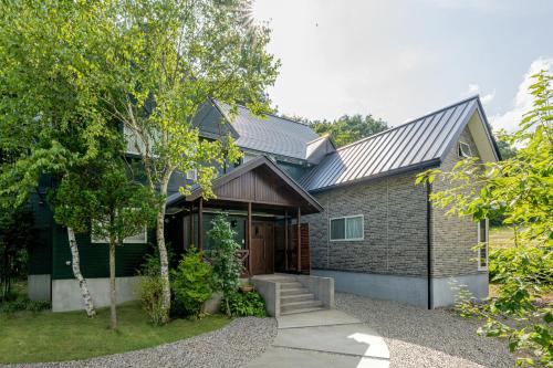a house with a gambrel roof and a driveway at Pension Green Lake in Gujo