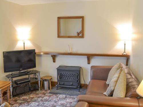 a living room with a couch and a television at Bodwi Isaf in Abersoch