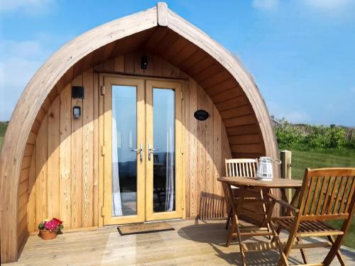 eine Holzhütte mit einer gewölbten Tür und einem Tisch in der Unterkunft Scenic Bay in Ludgvan