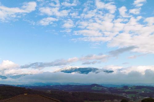 una montaña cubierta de nieve en el cielo con nubes en Ca la Nena Morena - Refugio cálido con chimenea y vistas al Montseny, en Vallgorguina