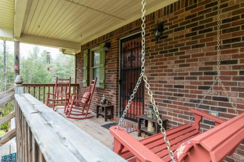 eine Veranda mit zwei roten Stühlen und einer Schaukel in der Unterkunft Hot Tub & WiFi -Carrie's Cottage - Red River Gorge in Pine Ridge