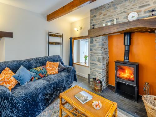 ein Wohnzimmer mit einer blauen Couch und einem Kamin in der Unterkunft Ivy Bush Cottage in Llanddewi-Brefi