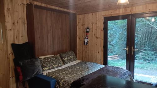 une chambre avec un lit et une grande fenêtre dans l'établissement Stream-side cabin and sauna, à Ballyduff