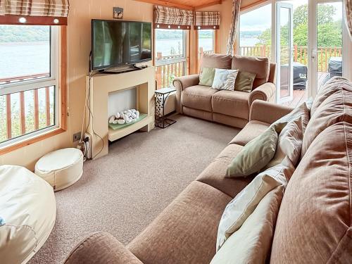 a living room with a couch and a tv at Badger Lodge in Burton