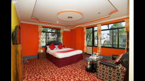 a bedroom with orange walls and a bed and a couch at Hotel Green View in Ilām