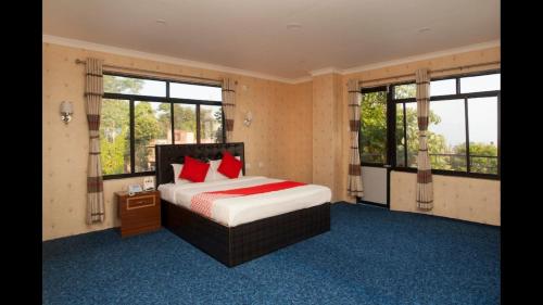 a bedroom with a bed with red pillows and windows at Hotel Green View in Ilām