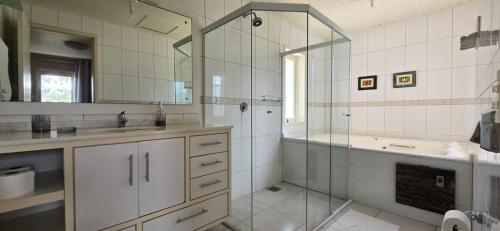 a bathroom with a shower and a sink and a mirror at Pousada Casa Campeche - Floripa in Florianópolis