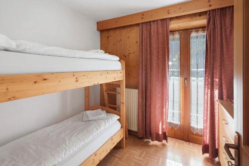 a bedroom with two bunk beds and a window at Ciasa Lino Rotic in Pozza di Fassa