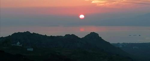 a sunset with the sun setting over the mountains at YouGa Nest in Vívlos