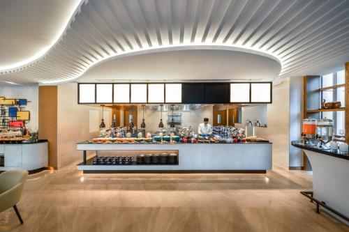 a kitchen with a counter with a chef behind it at Hyatt Place Dhaka Uttara in Dhaka