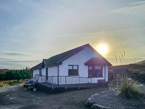 a small white house with the sun behind it at Pine View in Cairisiadar